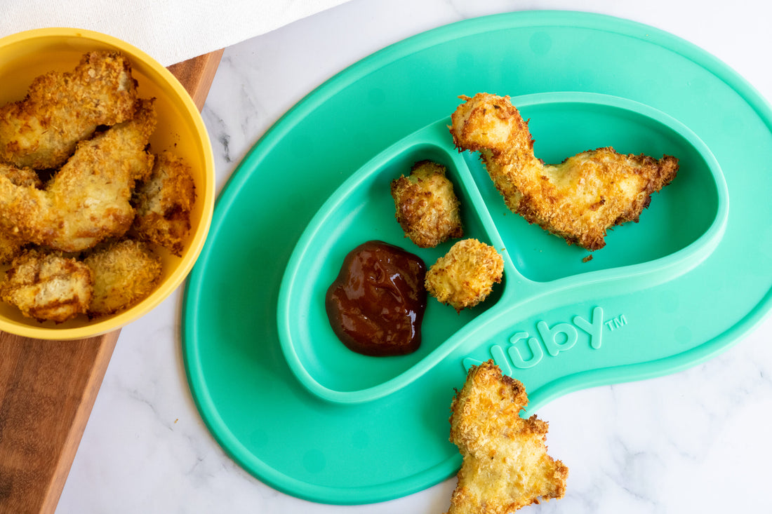 Homemade dinosaur shaped chicken nuggets with barbecue sauce in a blue-green kids bowl.
