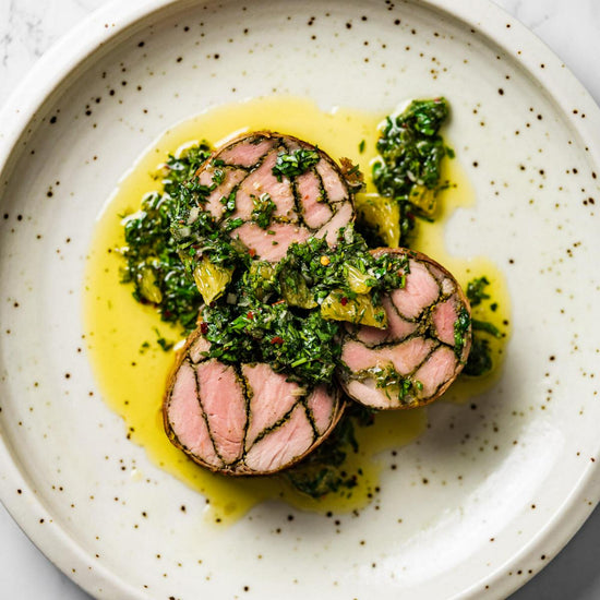 Mosaic pork tenderloin wrapped in prosciutto topped with chimichurri sauce