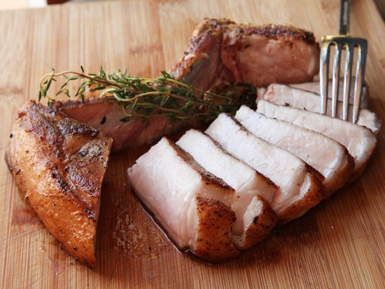 Sliced medium-rare pork chop on a cutting board with fresh thyme sprigs