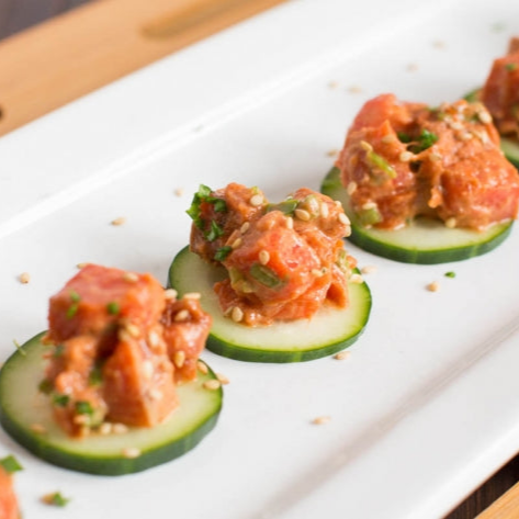 Salmon poke on cucumber rounds on a white platter