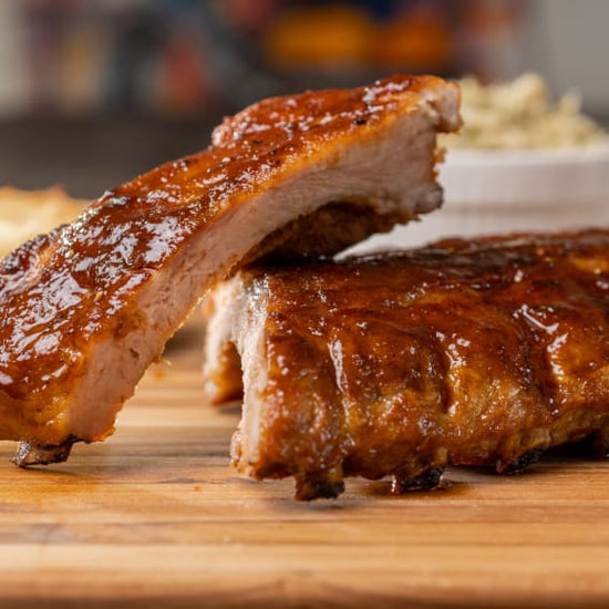 Sauce-glazed rack of ribs sliced in half on a cutting board