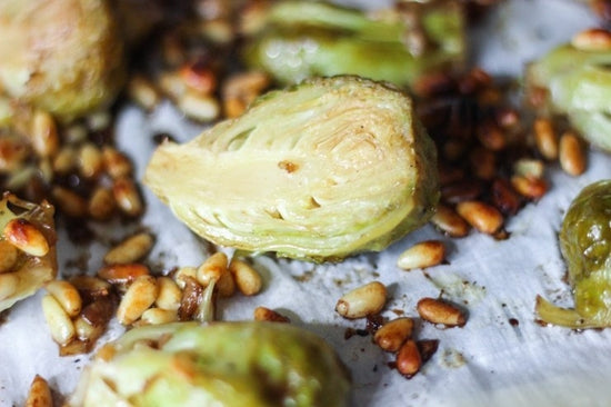 sliced sous vide brussels sprouts on a sheet pan with pine nuts