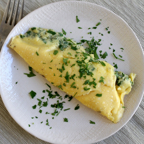 sous vide omelet on a white plate topped with chopped herbs