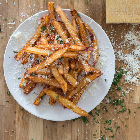 sous vide french fries on a white plate topped with cheese and herbs