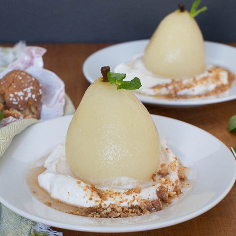poached pear on a bed of cream with cookie crumbs