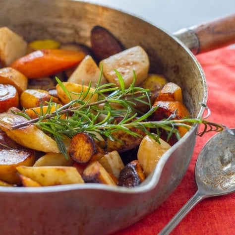 sous vide root vegetables topped with rosemary in a saucepan