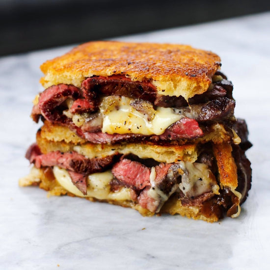 side view of halved short rib patty melt with cheese and onions