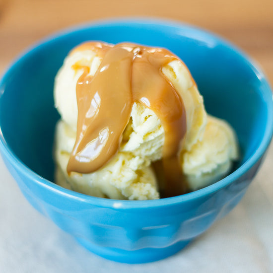 dulce de leche drizzled on vanilla ice cream in a blue bowl