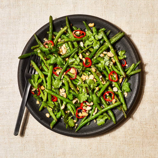 roasted green beans with chiles and nuts on a black plate