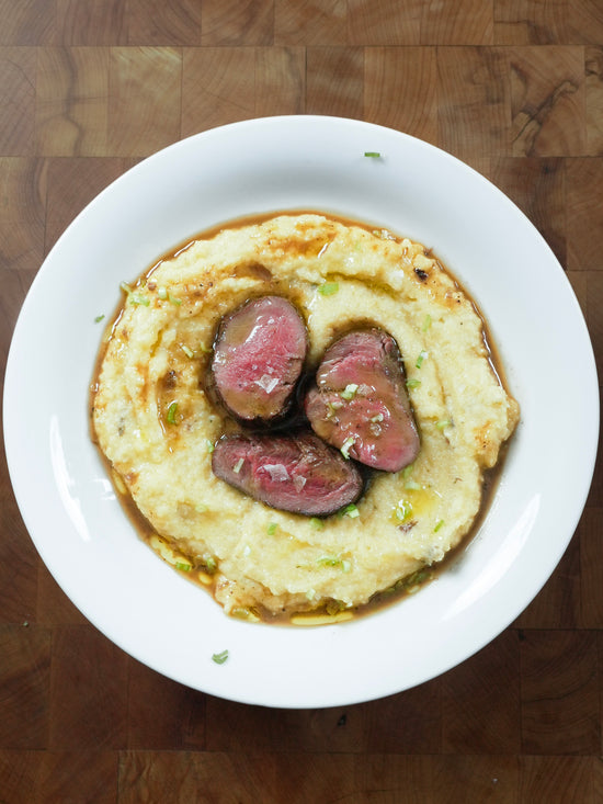 in Scheiben geschnittenes Elchfilet auf einem Polentaboden, überbacken mit Demiglace