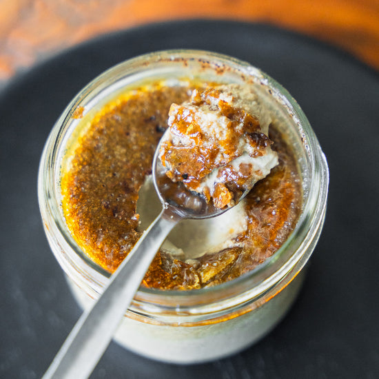 geknackte Crème brûlée im Glas mit einem Löffel, der einen Bissen herauslöffelt