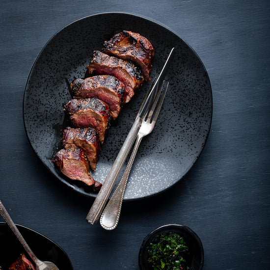 sliced venison tenderloin on a black plate