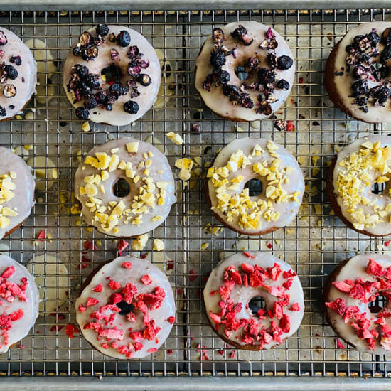 Donuts cozidos e glaceados numa grelha com coberturas de fruta desidratada